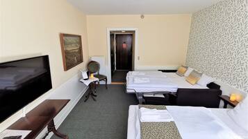 A hotel room with two beds, a TV, a desk with a chair, and a painting on the wall.