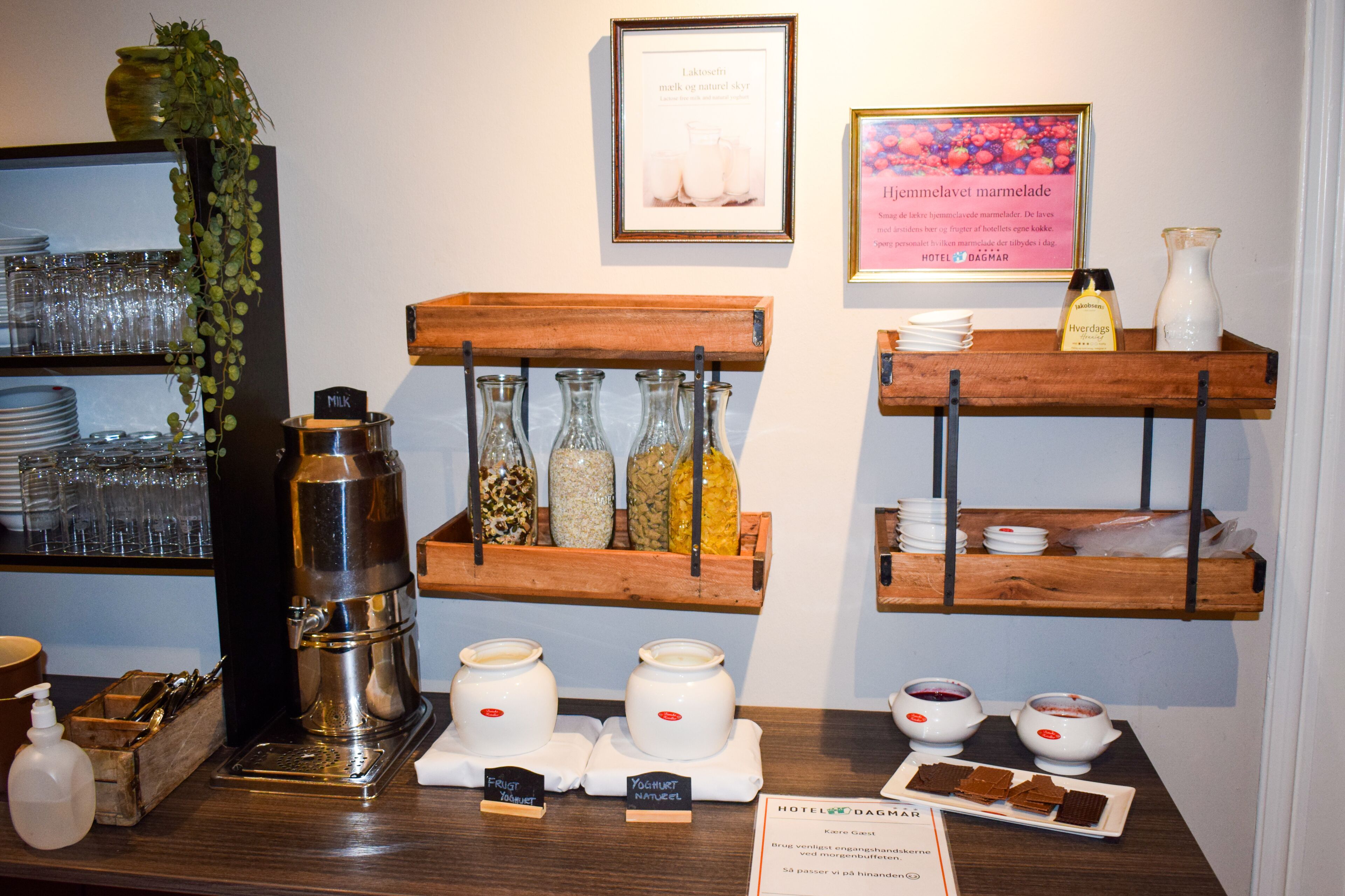 A hotel breakfast setup with a coffee machine, milk dispensers, and a variety of condiments and spreads.