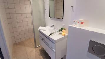 A modern bathroom with a white vanity, a glass shower enclosure, and a mirror above the sink.