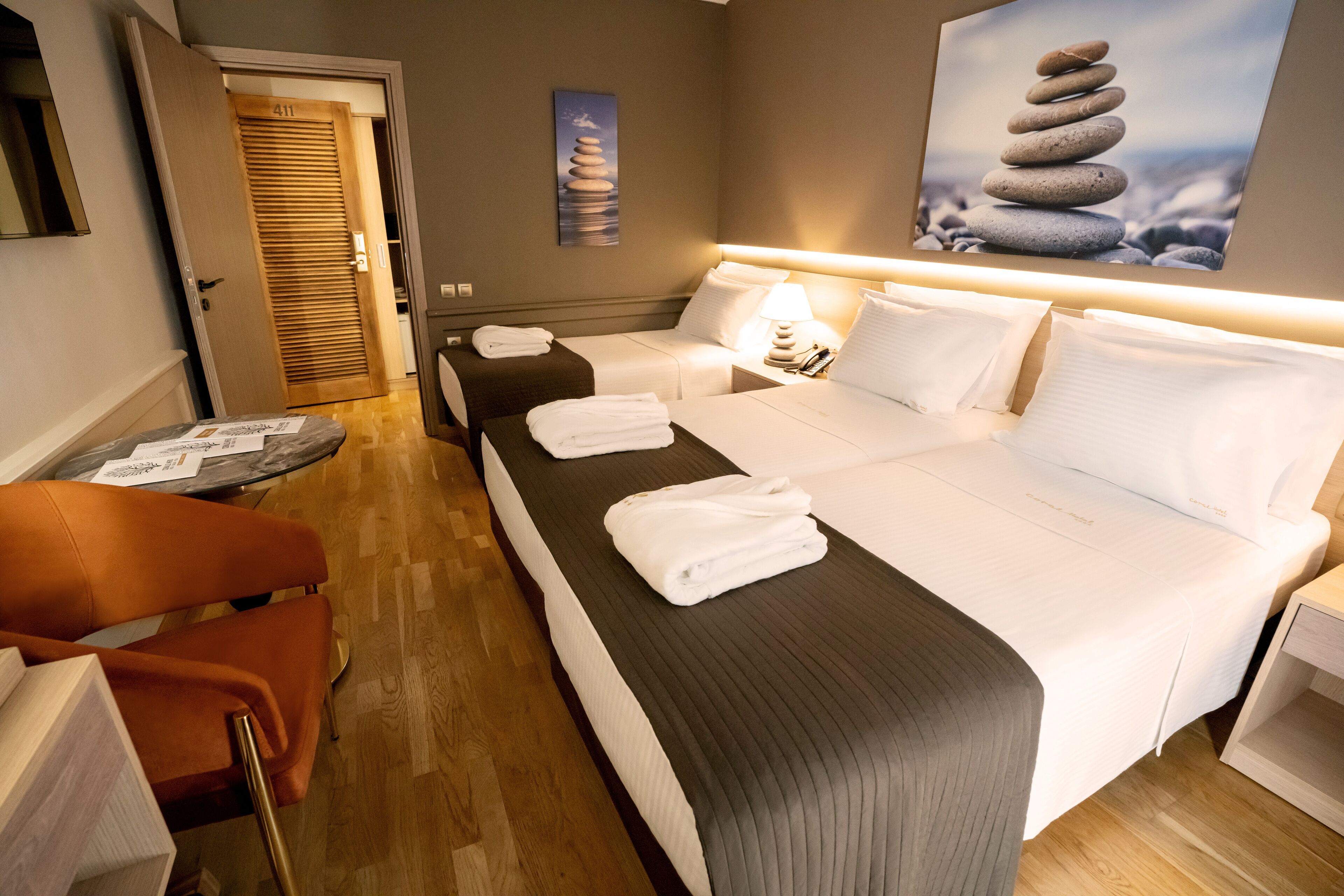 A hotel room with a large bed, two bedside tables, a chair, and a door leading to another room.