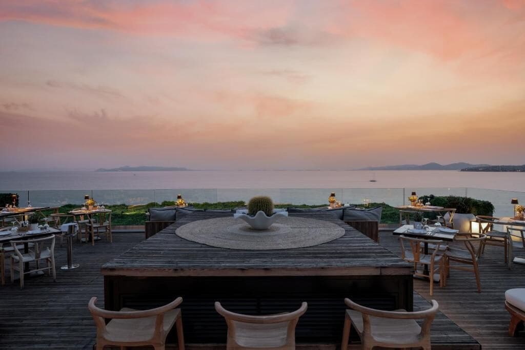 A wooden deck with outdoor seating and a view of the sea.