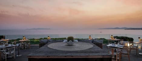 A wooden deck with outdoor seating and a view of the sea.