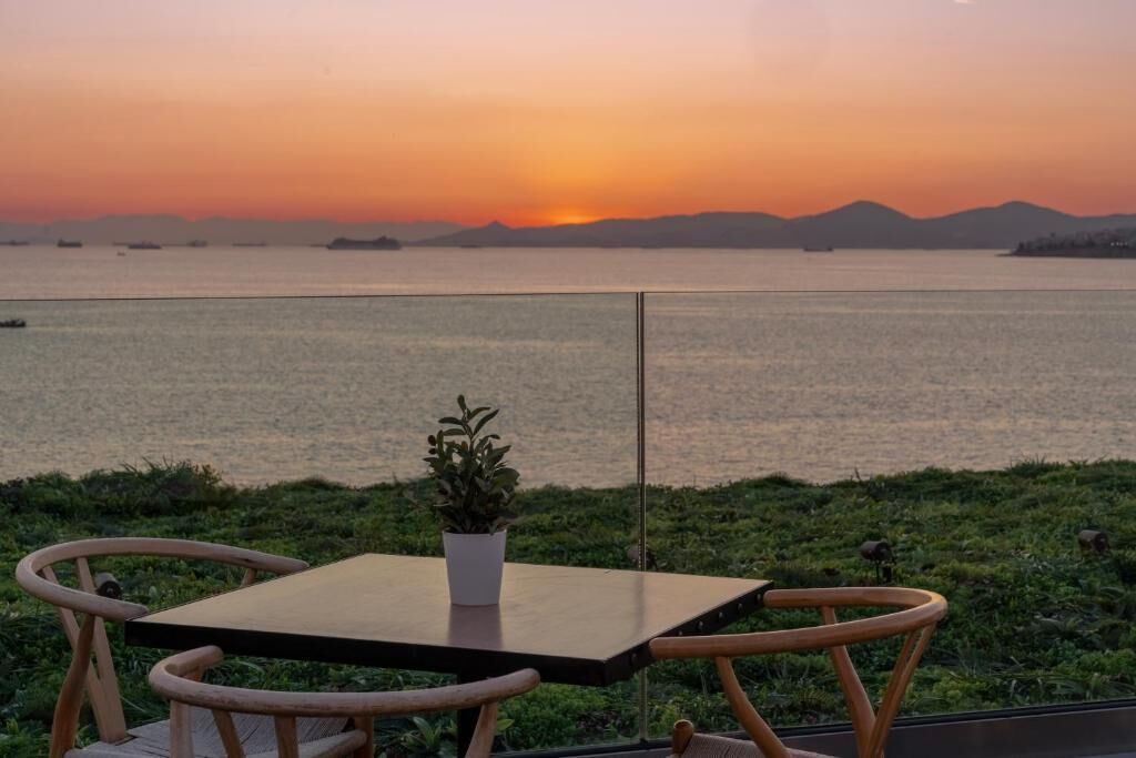 A table and chairs on a balcony overlooking a body of water with a sunset view.