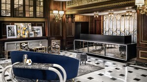Eine luxuriöse Lobby mit einem blauen Sofa, einer schwarzen Unterhaltungsecke und Kunstwerken an den Wänden.