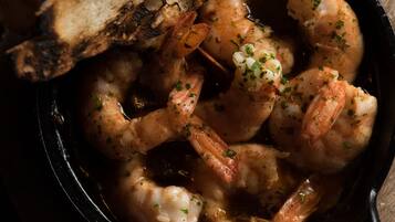 A close-up of a dish with shrimp and bread in a cast iron skillet.