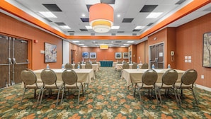 A conference room with a floral carpet, tables with chairs, and a large orange pendant light. - Forest Park Hotel by MDR (St. Louis)