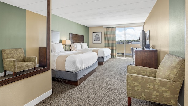 A hotel room with two beds, a chair, a desk, and a large window. - Forest Park Hotel by MDR (St. Louis)