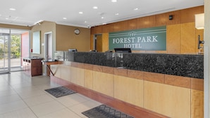 A reception desk with a sign reading "Forest Park Hotel" and a clock on the wall. - Forest Park Hotel by MDR (St. Louis)