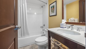 A bathroom with a bathtub, toilet, and sink. - Forest Park Hotel by MDR (St. Louis)