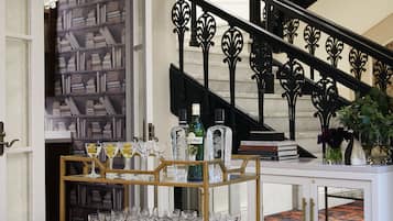 Una scala con ringhiere nere decorate, una libreria con libri e un'area bar con bicchieri e bottiglie.