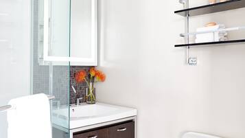 A modern bathroom with a glass shower enclosure, a white sink, and a dark wooden cabinet.