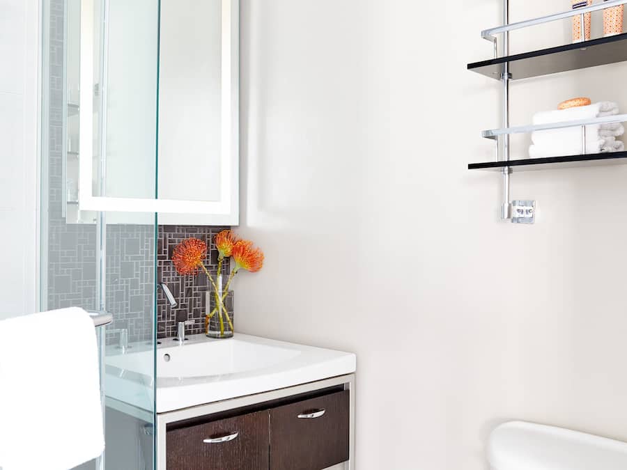 A modern bathroom with a glass shower enclosure, a white sink, and a dark wooden cabinet.