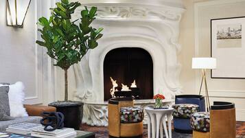 A cozy living room with a fireplace, comfortable seating, and a decorative plant.