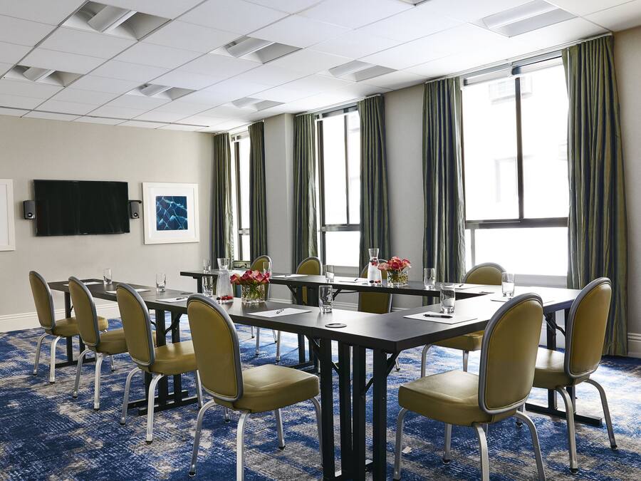 A conference room with a long table, chairs, a TV, and artwork on the walls.