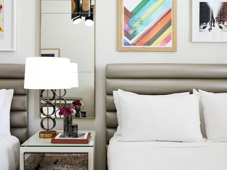 Una habitació d'hotel de disseny modern, amb un llit gran, una taula de nit amb una làmpada i obra d'art a les parets.
