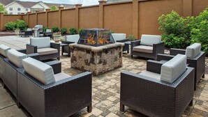An outdoor patio with wicker furniture, a stone fire pit, and a view of neighboring houses. - Courtyard by Marriott Knoxville Cedar Bluff (Knoxville)