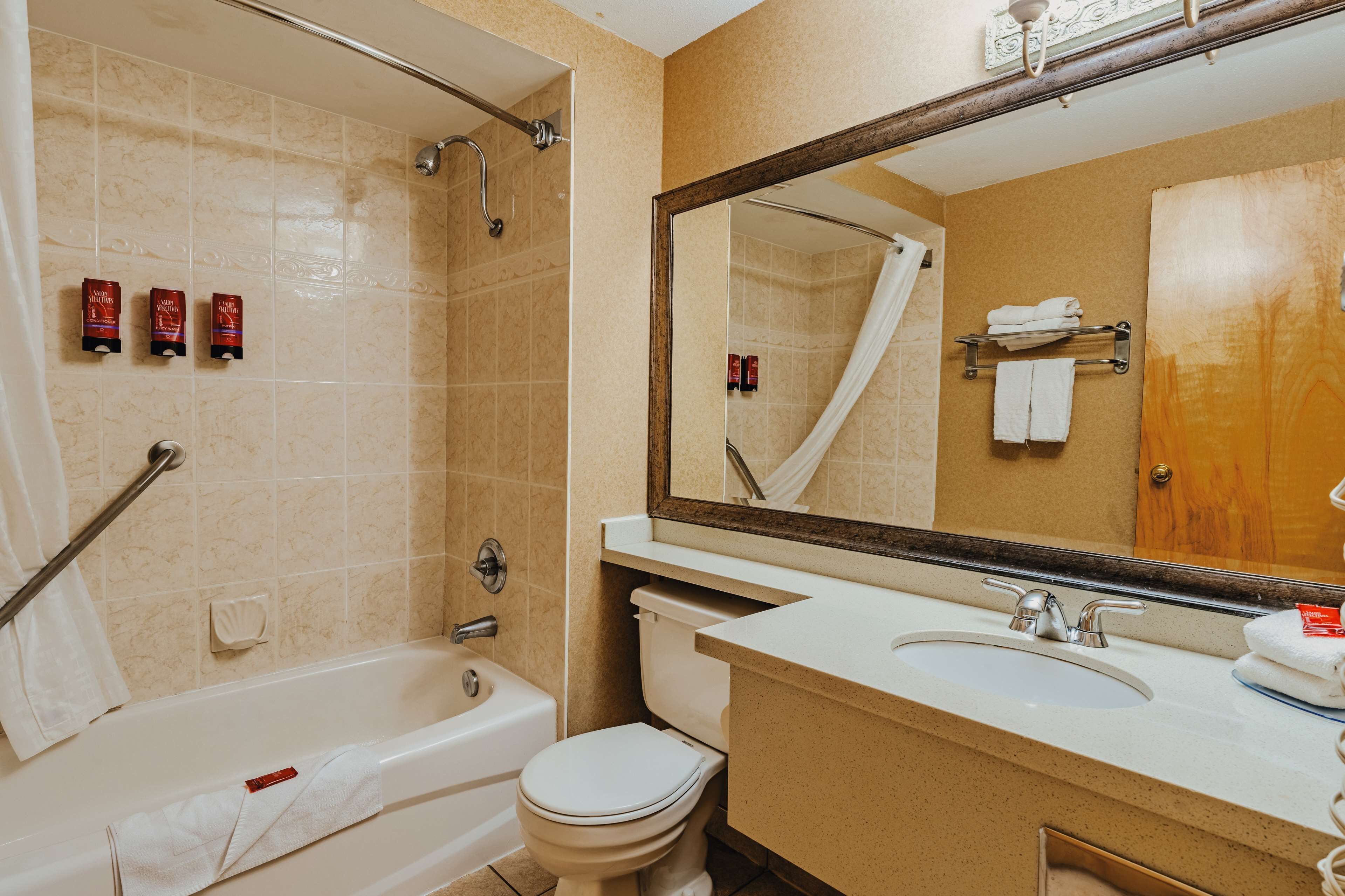 A bathroom with a bathtub, toilet, sink, and a large mirror.
