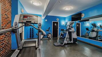 A gym with treadmills, elliptical machines, and a mirrored wall.