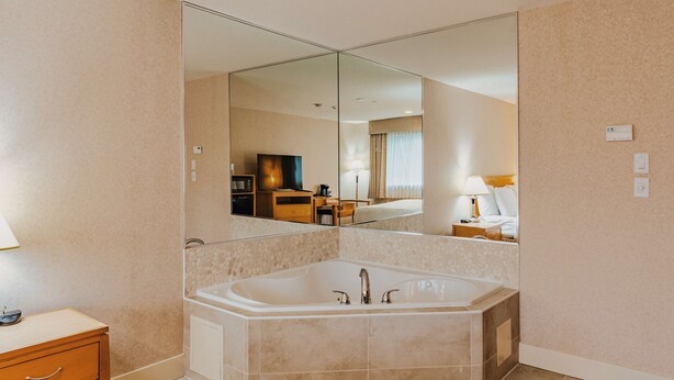 A modern bathroom with a large mirror, a bathtub, and a vanity with a sink.