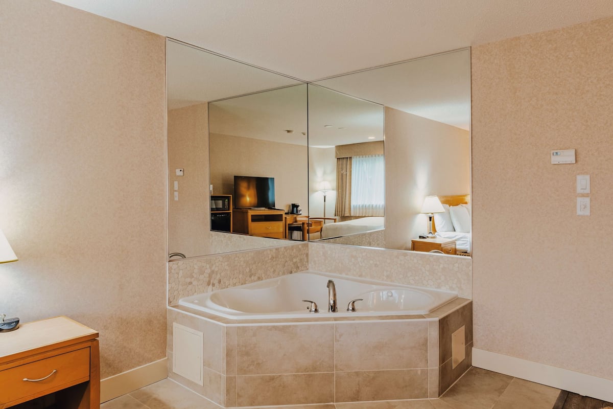 Un baño moderno con un espejo grande, una bañera y un tocador con lavamanos.