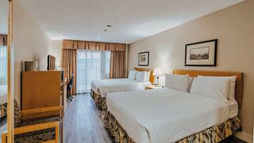 Ein Hotelzimmer mit zwei Betten, einem Schreibtisch, einem Stuhl und einem fenster mit Vorhängen.