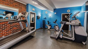 A gym with treadmills, elliptical machines, and a mirror.