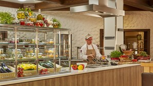 Un chef préparant des plats dans une cuisine moderne, avec un assortiment de produits frais et de condiments à portée de main.