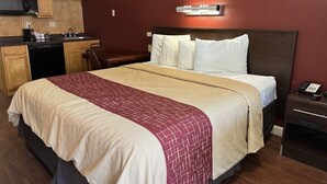 Hotellihuone, jossa on sänky, työpöytä, mikroaaltouuni ja kahvinkeitin.