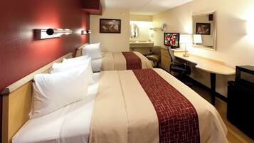 A hotel room with two beds, a desk, a chair, a television, and a mirror.