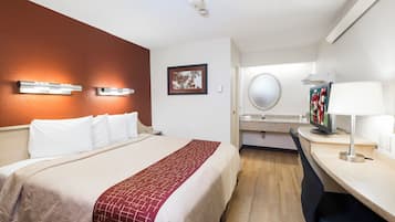 A hotel room with a bed, bedside table, lamp, and a mirror.