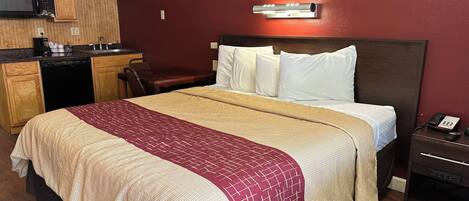 Una habitación de hotel con una cama, un escritorio, un microondas y un teléfono.
