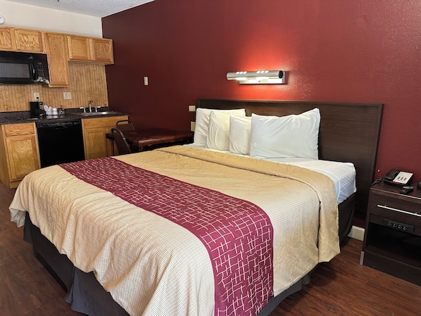 Una habitación de hotel con una cama, un escritorio, un microondas y un teléfono.