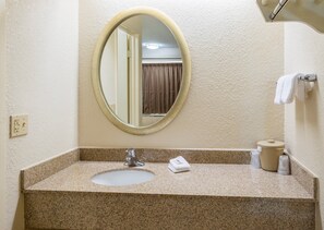 A bathroom with a granite countertop, a sink, a mirror, and a towel rack. - Red Roof Inn Parkersburg (Parkersburg)