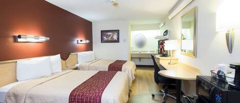 Habitación de hotel con dos camas, un escritorio, una silla, un televisor y un minibar.