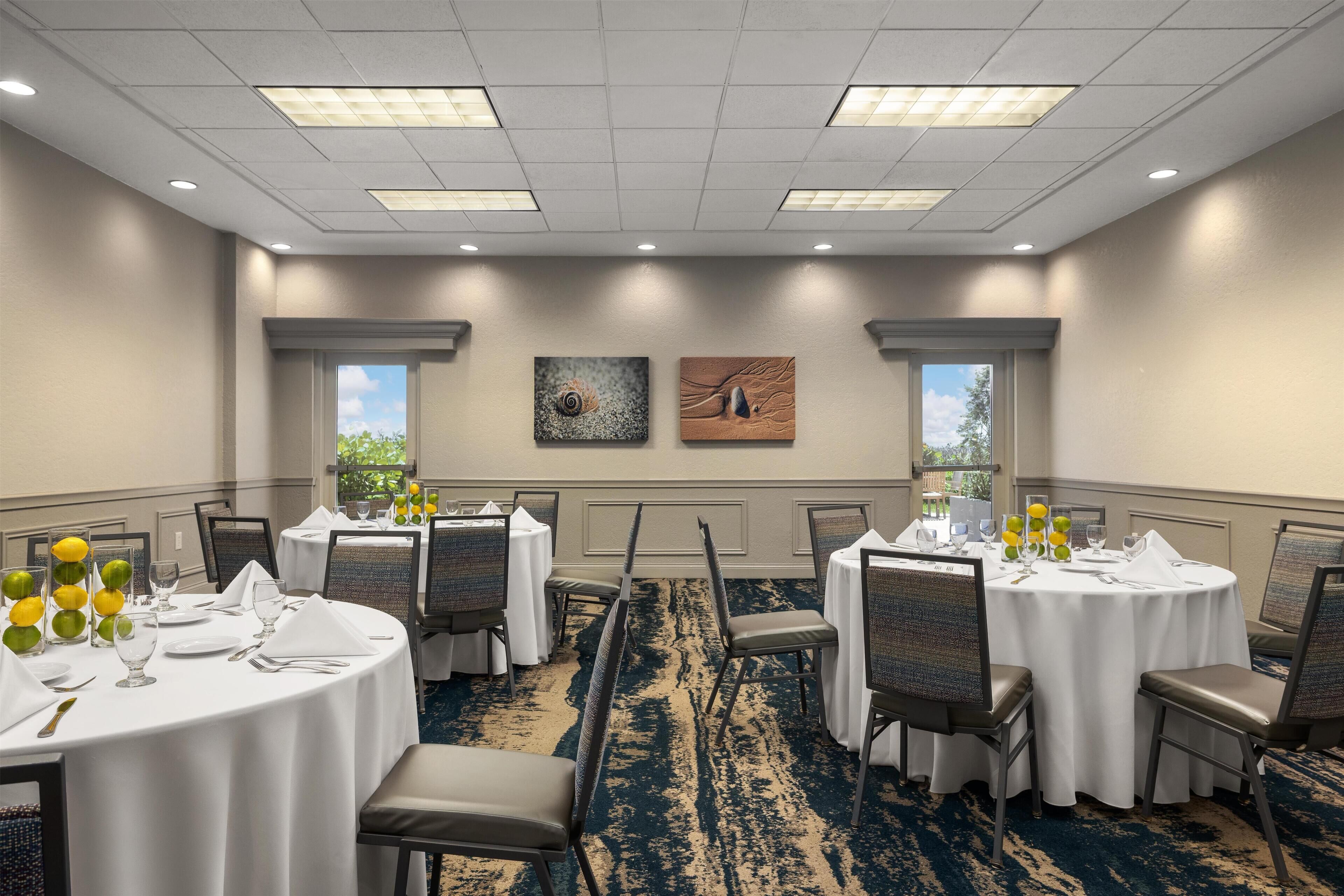 A conference room with round tables, chairs, and artwork on the walls.