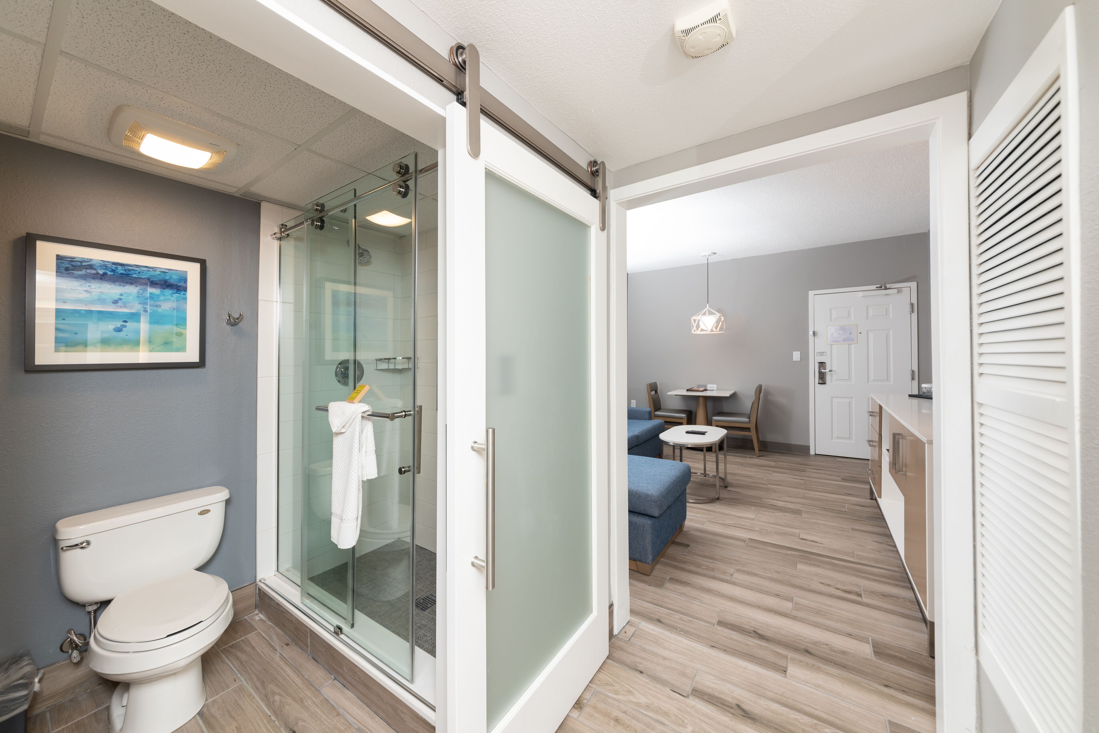 A modern bathroom with a glass shower enclosure, a toilet, and a framed picture on the wall.