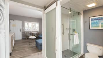 A modern bathroom with a glass-enclosed shower, a toilet, and a seating area with a table and chairs.