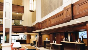 Eine großzügige Lobby mit einer Rezeption, einer Sitzecke und einer hohen Decke mit Holzverkleidung.