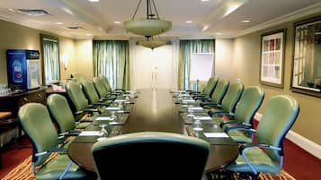 A conference room with a long table, green chairs, and a water dispenser.