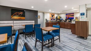 A modern restaurant with blue upholstered booths, a wooden bar area, and a kitchen in the background. - Best Western Atlanta-Marietta Ballpark Hotel (Marietta)