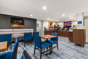 Un restaurante moderno con asientos tapizados en azul, una zona de bar de madera y una cocina al fondo.