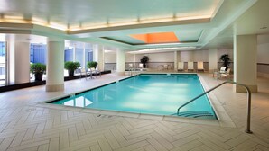 An indoor swimming pool with a herringbone floor pattern, surrounded by columns and potted plants. - Embassy Suites by Hilton Washington DC Chevy Chase Pavilion (Washington)