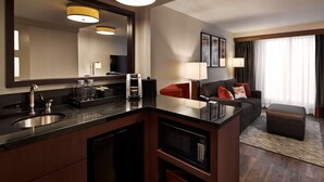 A modern hotel room with a kitchen area, a large mirror, a sofa, and a window with curtains. - Embassy Suites by Hilton Washington DC Chevy Chase Pavilion (Washington)