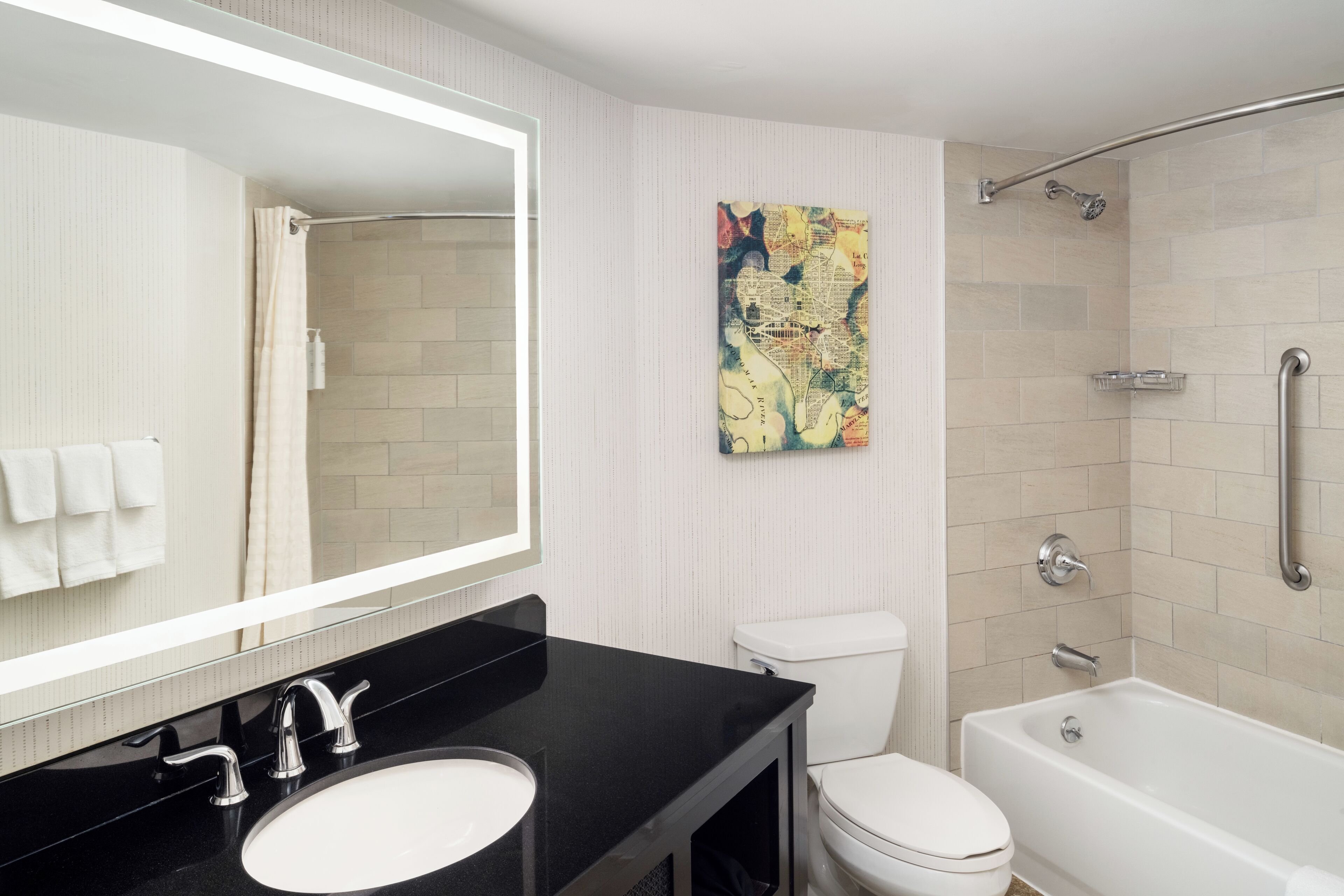 A modern bathroom with a black sink, white toilet, and a bathtub.