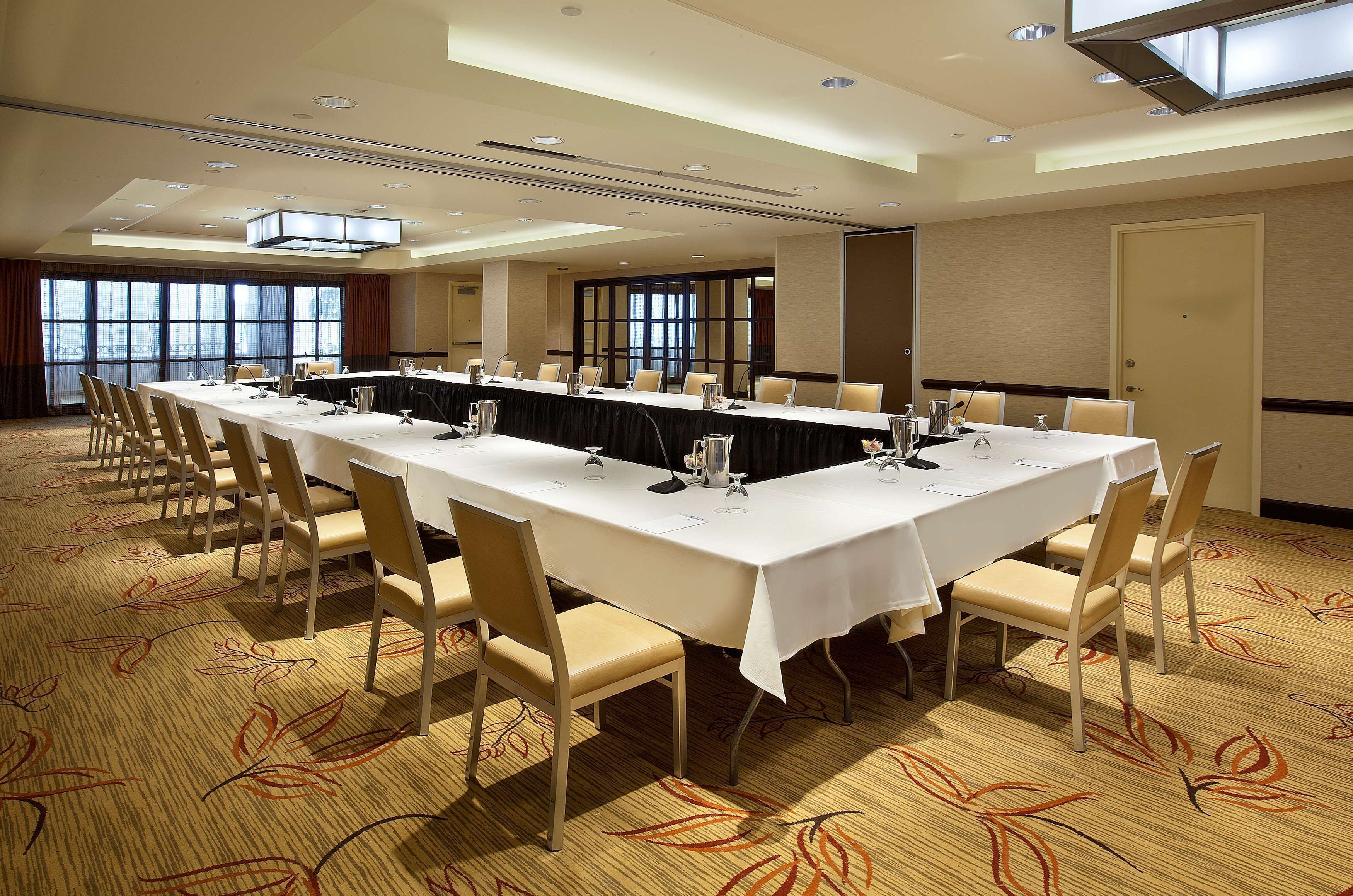 A conference room with a long table, chairs, and a carpeted floor.