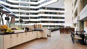 A modern hotel lobby with multiple floors, a central counter with fresh fruit, and a spacious seating area. - Embassy Suites by Hilton Washington DC Chevy Chase Pavilion (Washington)