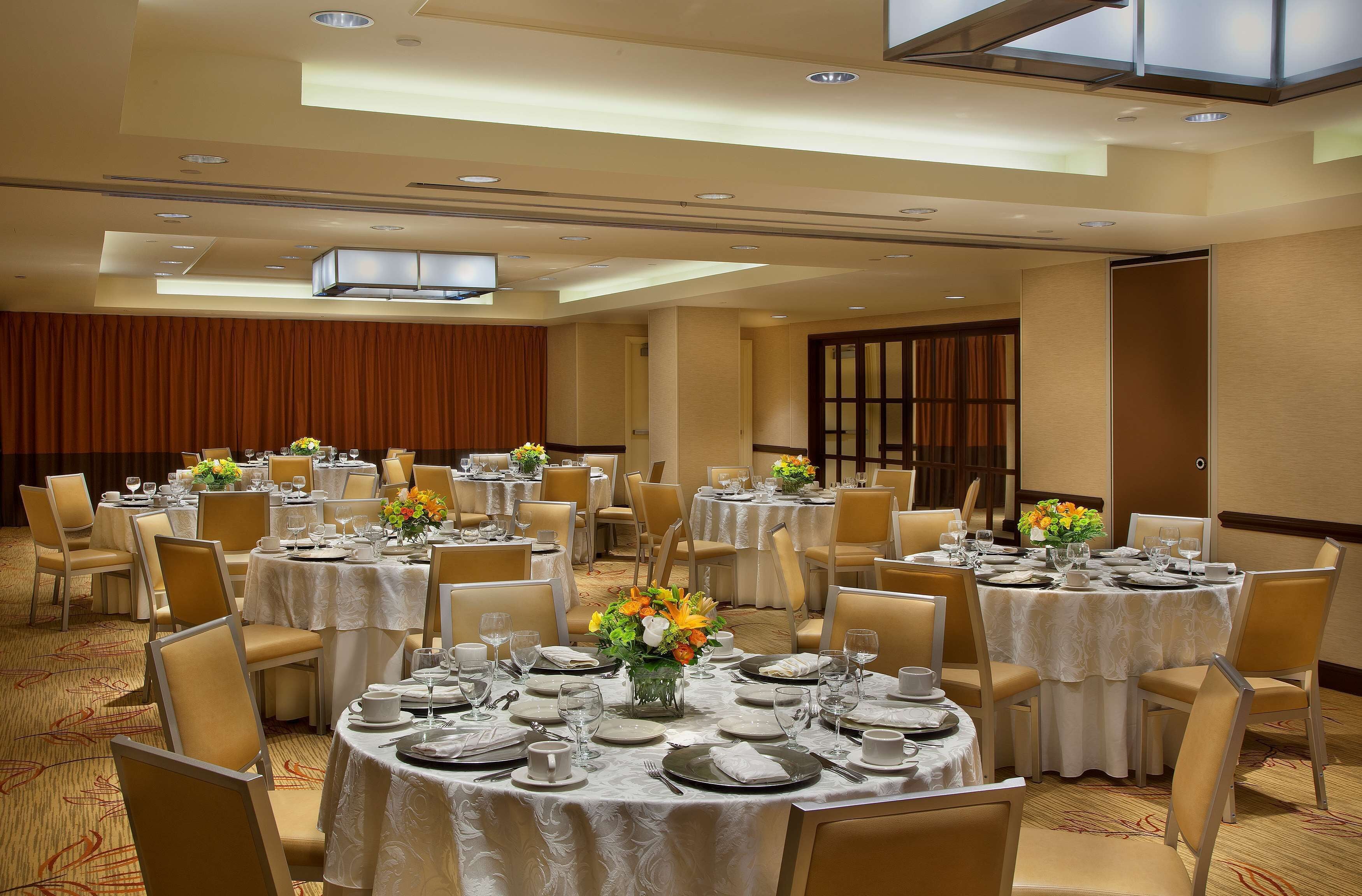 A banquet hall with round tables set for dining, featuring white tablecloths and floral centerpieces.