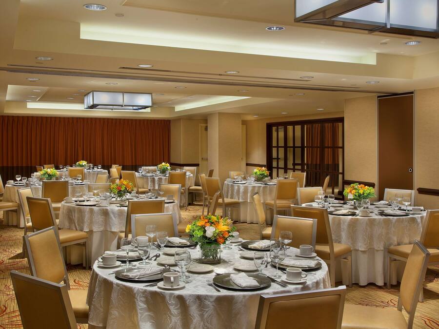 A banquet hall with round tables set for dining, featuring white tablecloths and floral centerpieces.