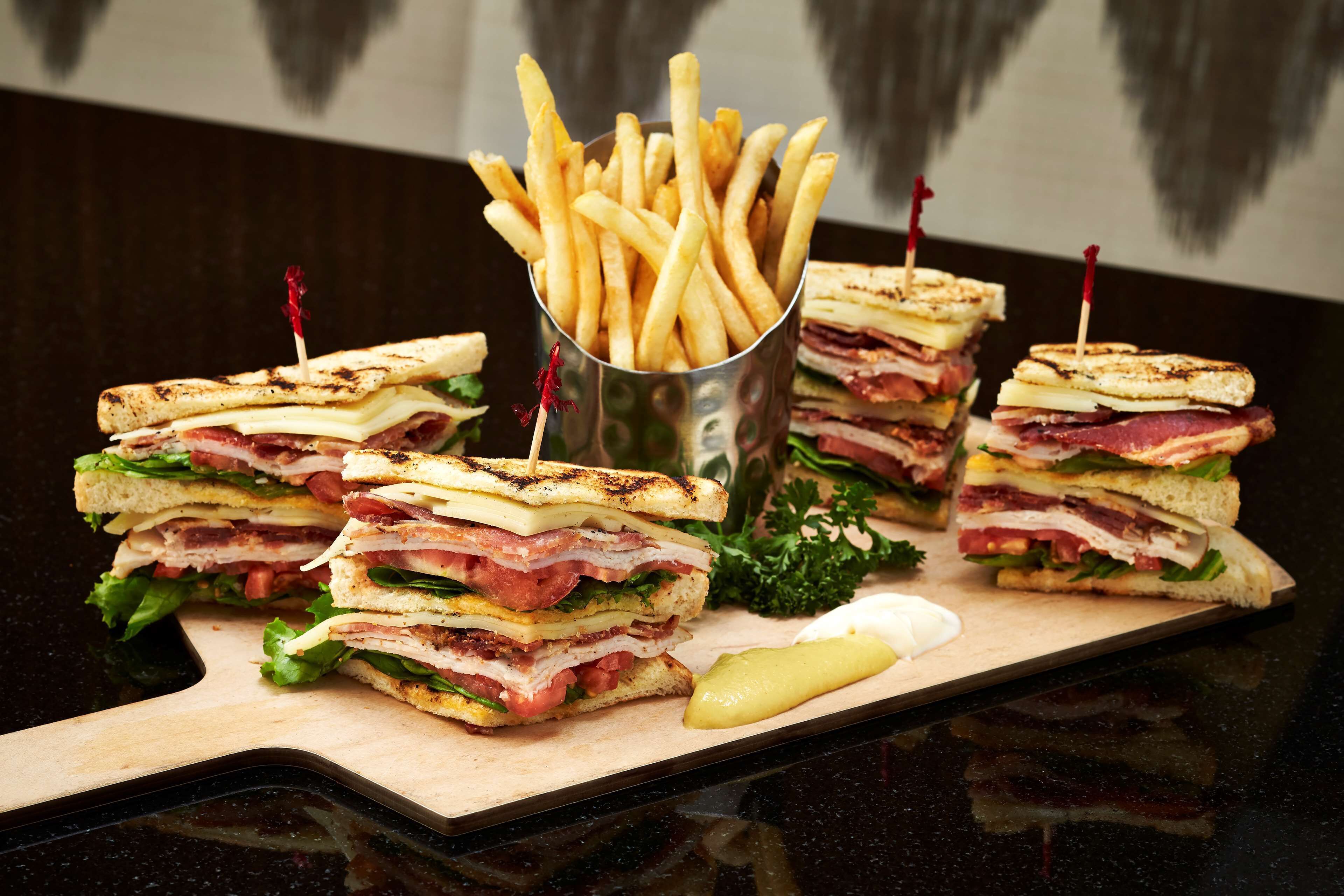 A sandwich with a side of fries and a pickle on a wooden board.