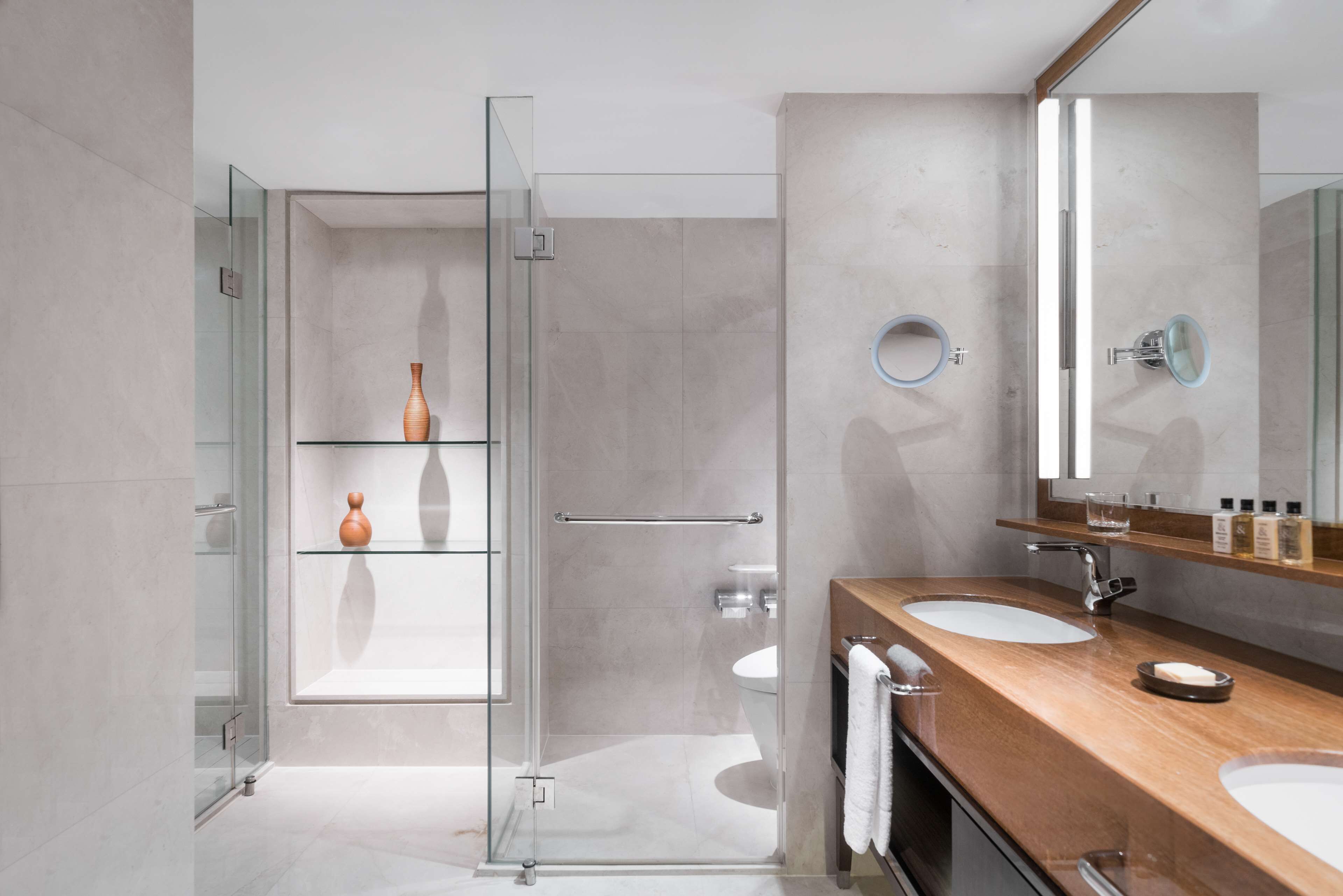 A modern bathroom with a glass shower enclosure, two sinks, and a large mirror.